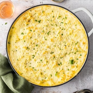 Tuna and Potato Pie, in a round white cast iron dish, with a green cloth on the edge.