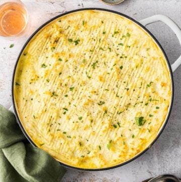 Tuna and Potato Pie, in a round white cast iron dish, with a green cloth on the edge.