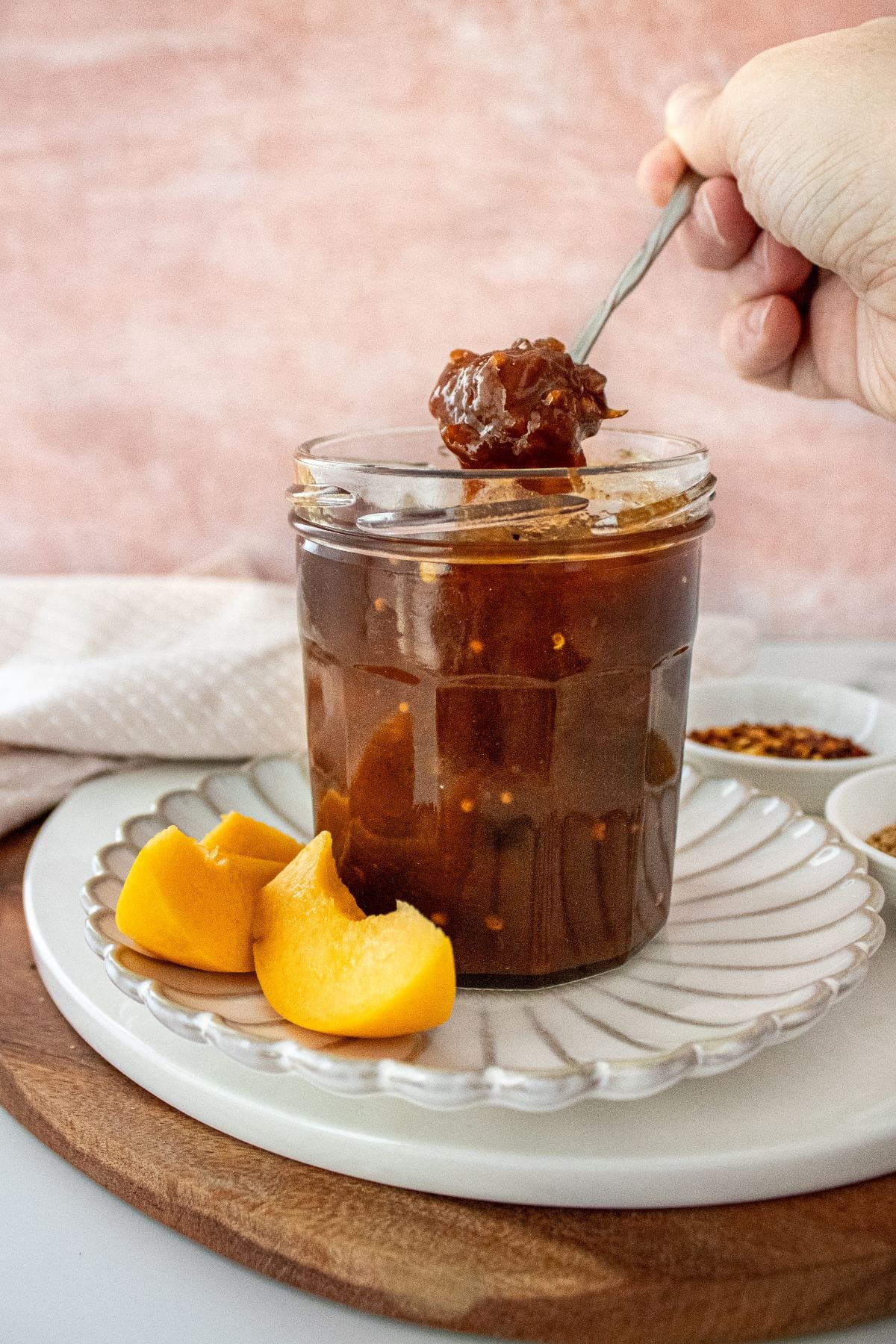 Open jar of Apricot Chutney on a small white plate, with a spoon scooping up some chutney.