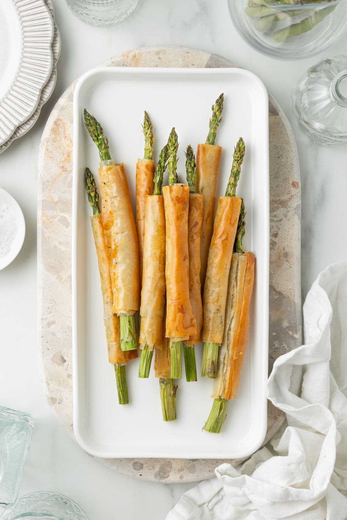 White Platter of Asparagus Filo Rolls, sitting on a marble board.