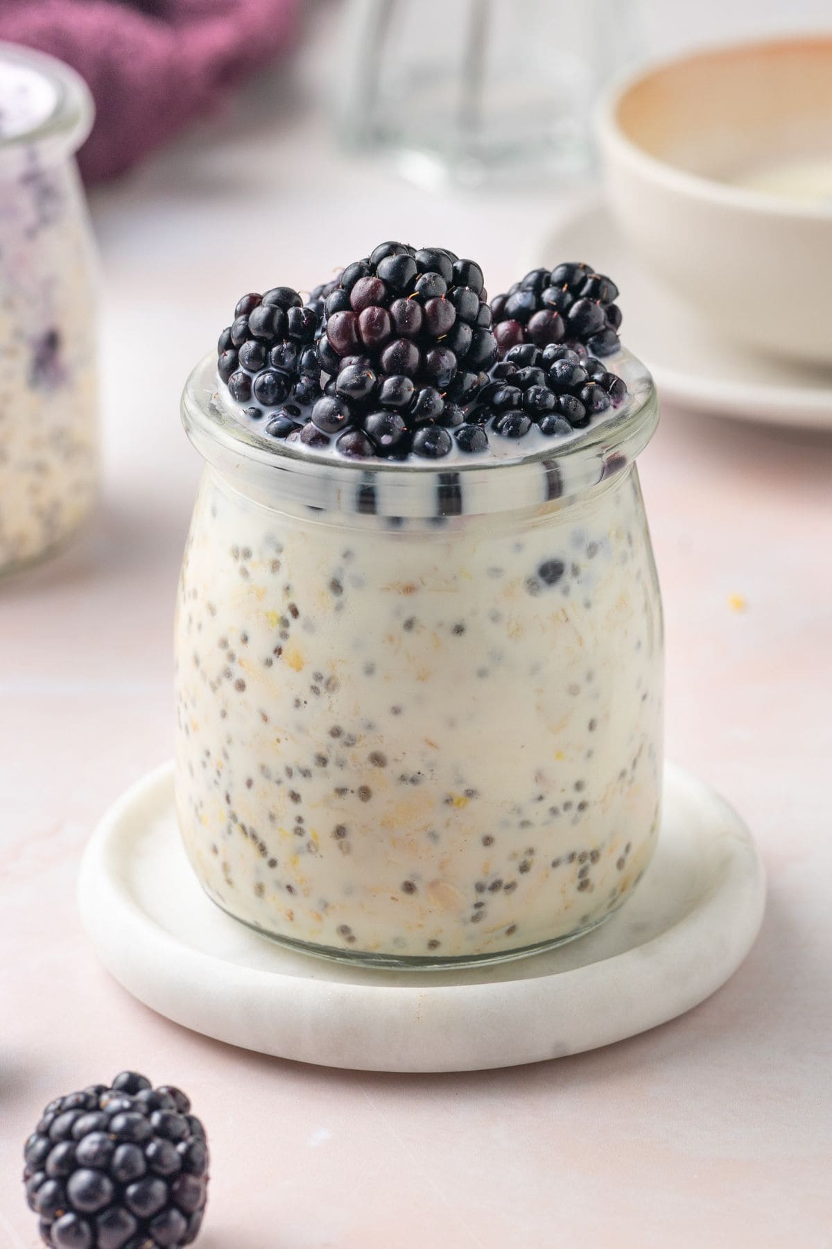 Jar of Blackberry Overnight Oats, sitting on a small white saucer.