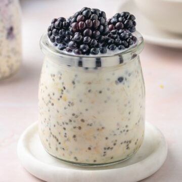Jar of Blackberry Overnight Oats, sitting on a small white saucer.