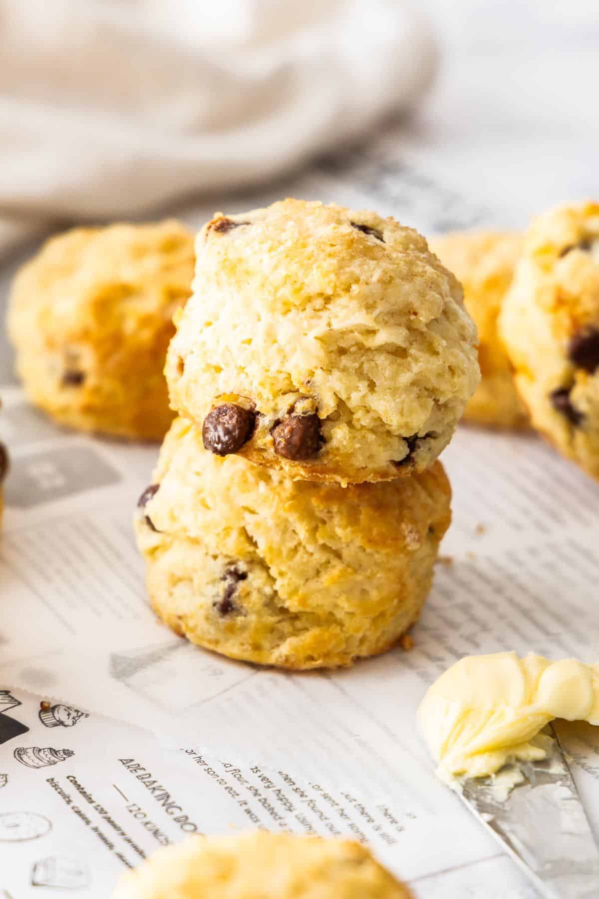 Chocolate Chip Scones sitting on some baking paper, with a knife with some butter on the edge.