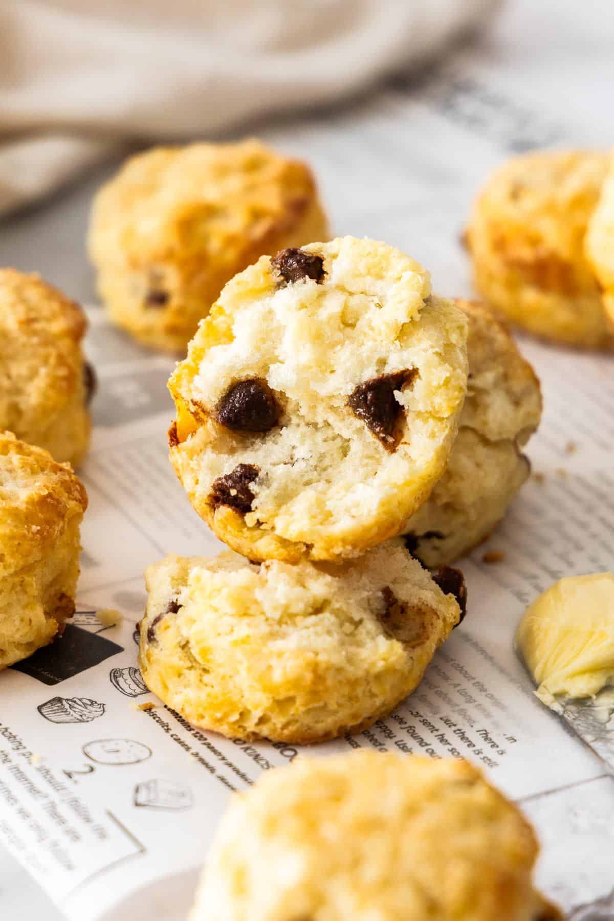 Chocolate Chip Scones sitting on some baking paper, with one cut in half to show the inside.