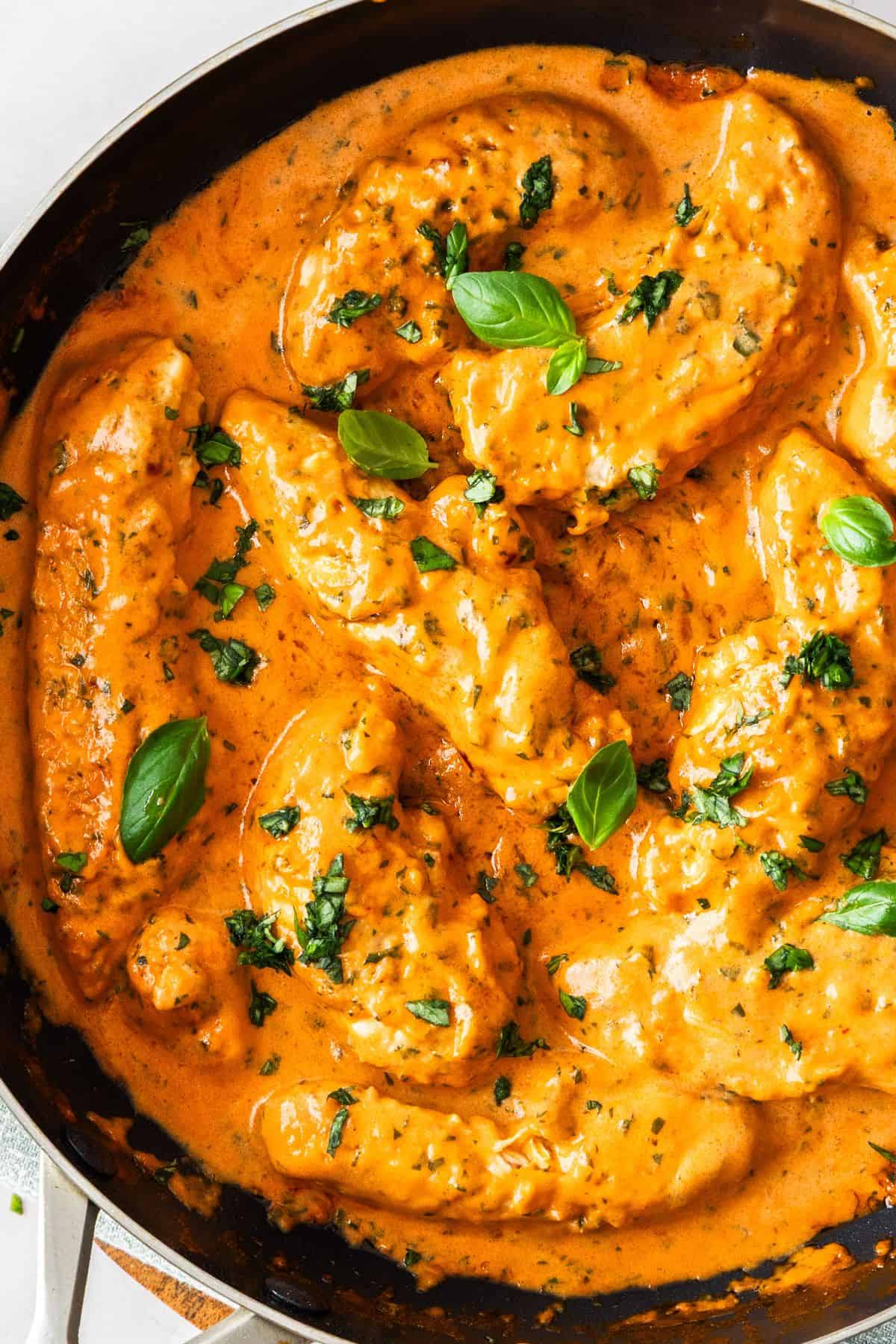 Frying pan with Creamy Tomato Chicken, garnished with some fresh basil.