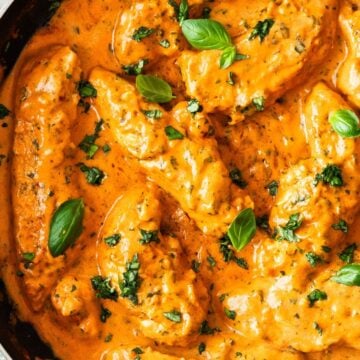 Frying pan with Creamy Tomato Chicken, garnished with some fresh basil.