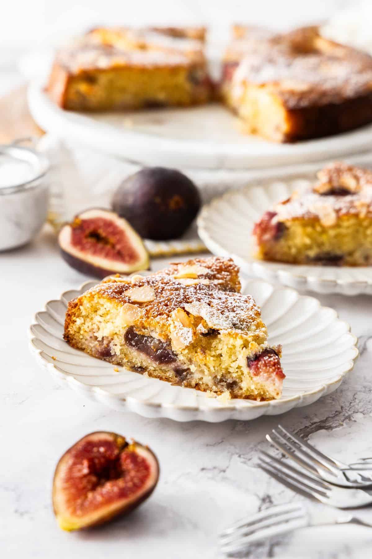 Gluten-Free Fig Cake, with two slices cut on small white plates, with some fig slices around the edge.