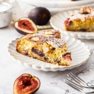 Gluten-Free Fig Cake, with two slices cut on small white plates, with some fig slices around the edge.