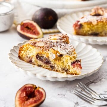 Gluten-Free Fig Cake, with two slices cut on small white plates, with some fig slices around the edge.