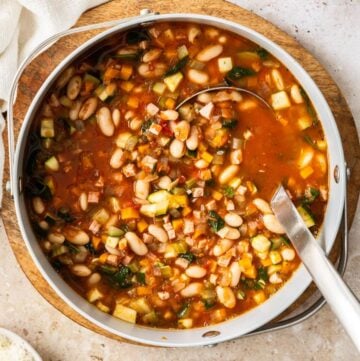 Saucepan full of Ham and Cannellini Bean Soup, with a ladle resting in the pot.