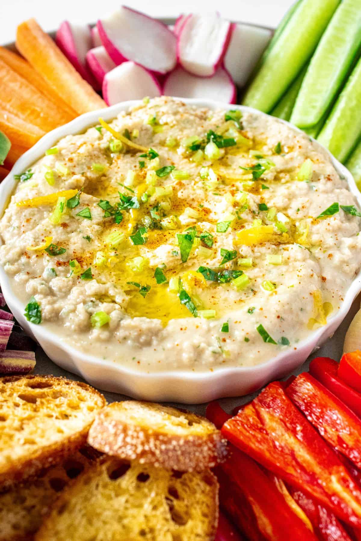 Dip platter featuring Mediterranean Tuna and White Bean Dip and a selection of sliced vegetables and some toasts.