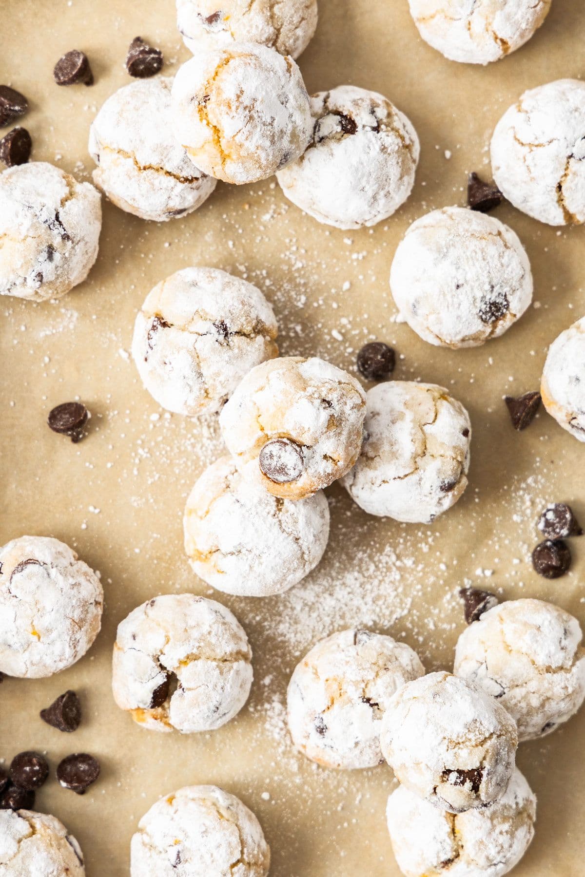 Baked Almond Flour Chocolate Chip Cookies on some baking paper, with some chocolate chips sprinkled around.