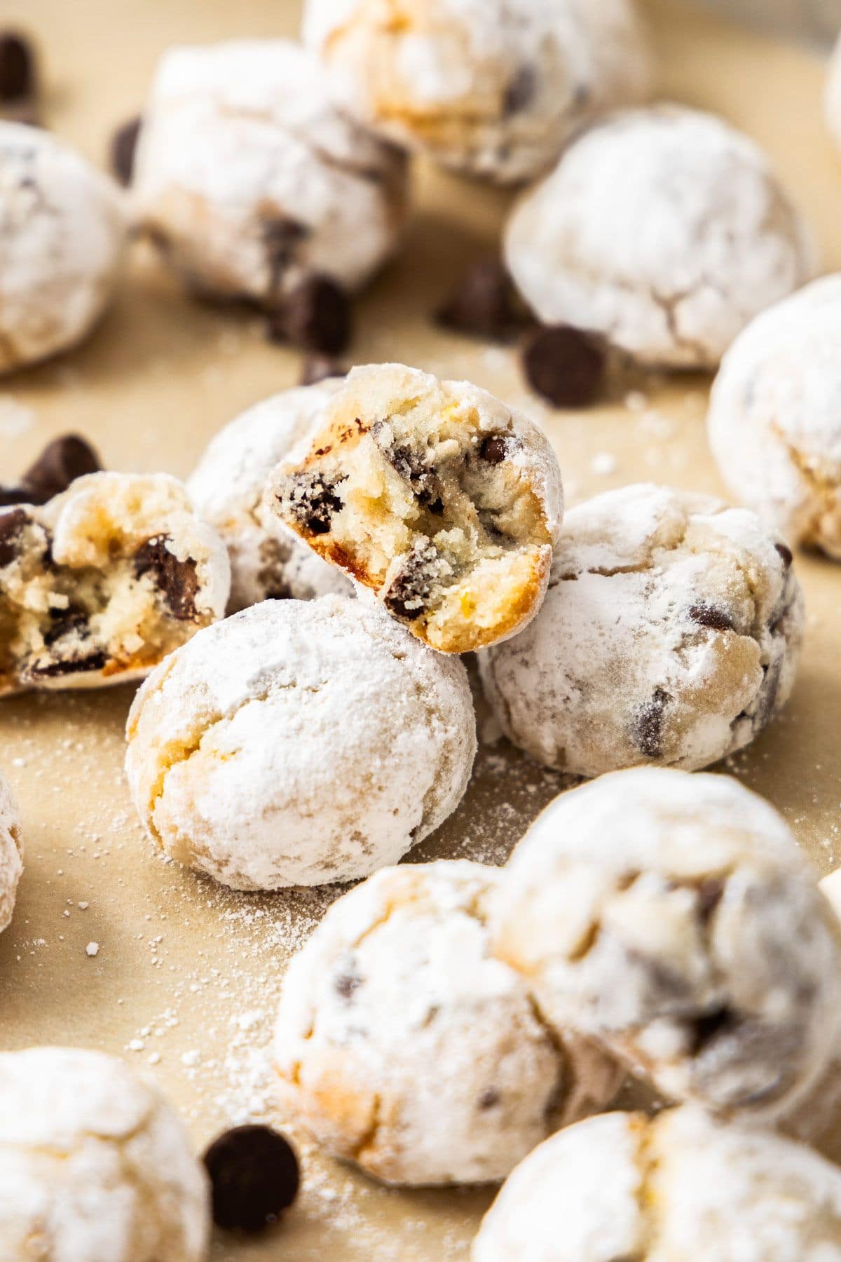 Almond Flour Chocolate Chip Cookies on a baking paper lined tray, with one broken in half.
