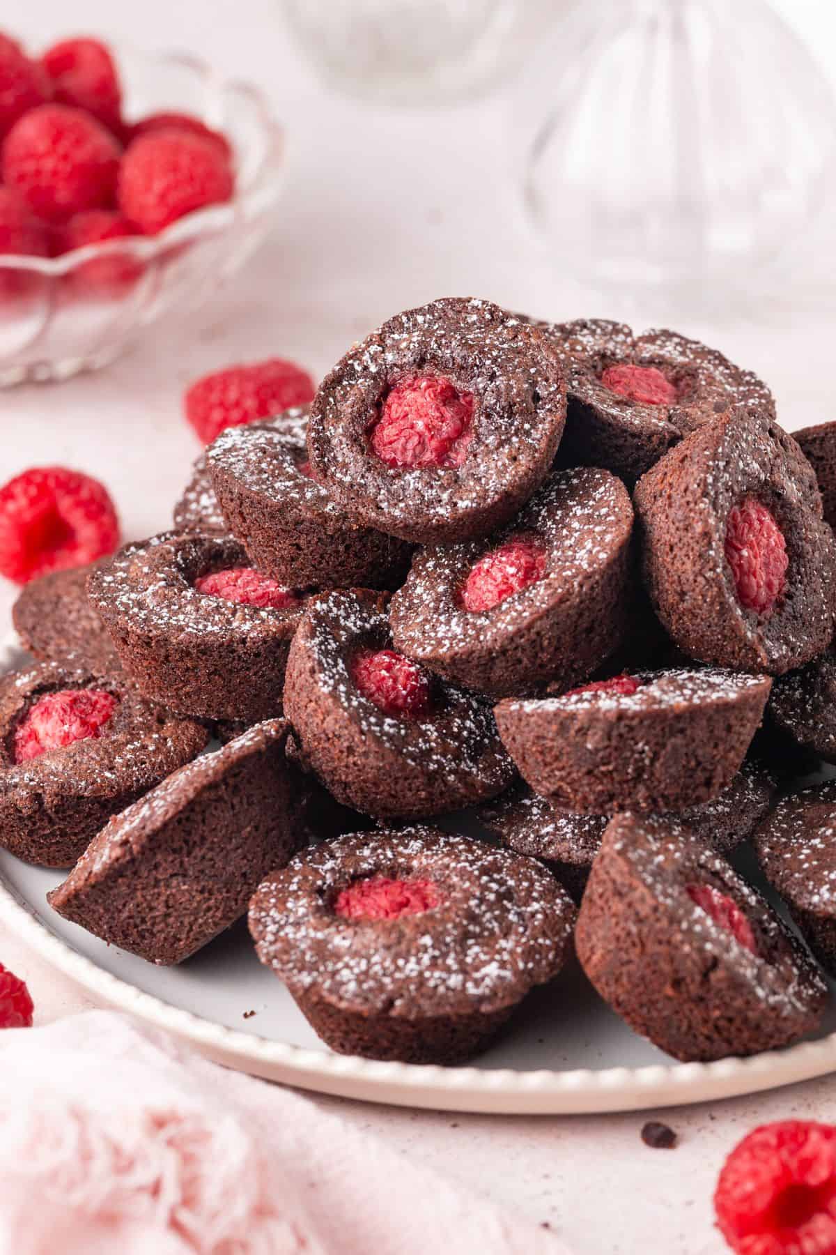Round white plate with Chocolate Raspberry Bites dusted with icing/powdered sugar.