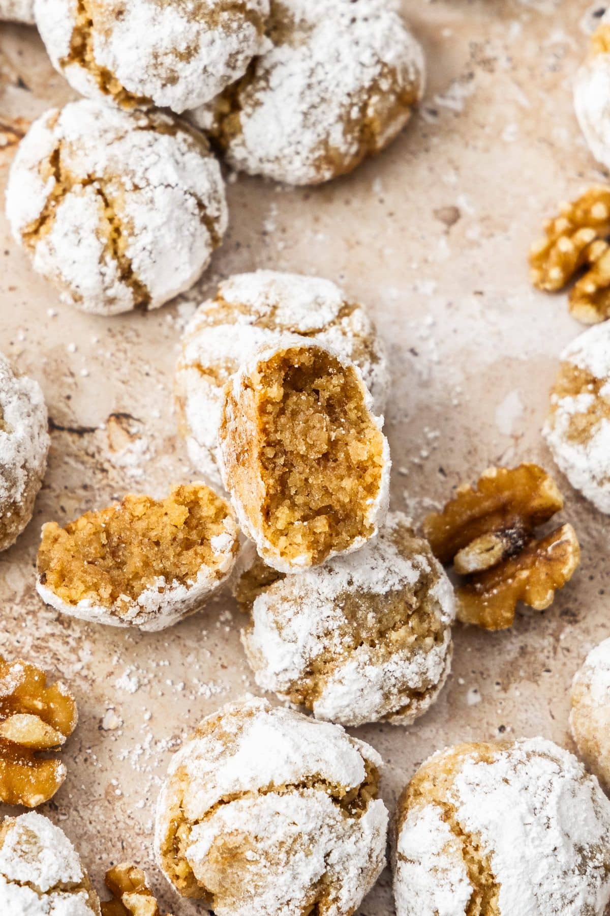 Baked Walnut Cookies on a baking paper lined tray, with one broken in half.