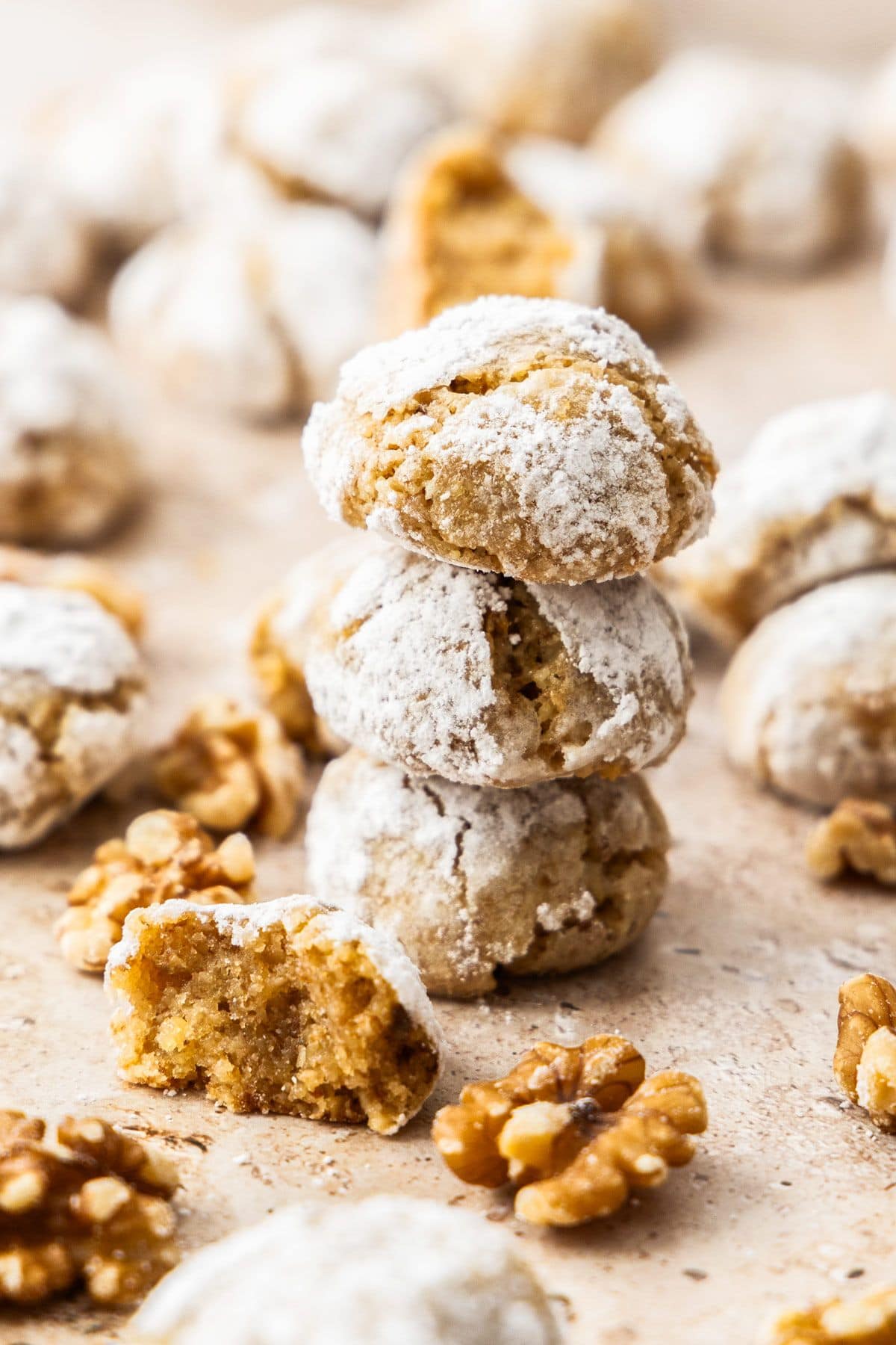 Stack of three Walnut Cookies, with more cookies spread on a baking tray.