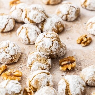 Baked Walnut Cookies on some baking paper, with some pieces of walnut sprinkled around.