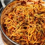 Mushroom and Tomato Pasta, garnished with finely chopped parsley, in a large skillet, sitting on a wooden board.