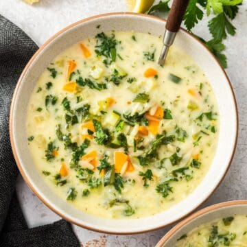 Round grey bowl with a serving of Creamy Orzo Vegetable Soup, with a spoon resting in the bowl.