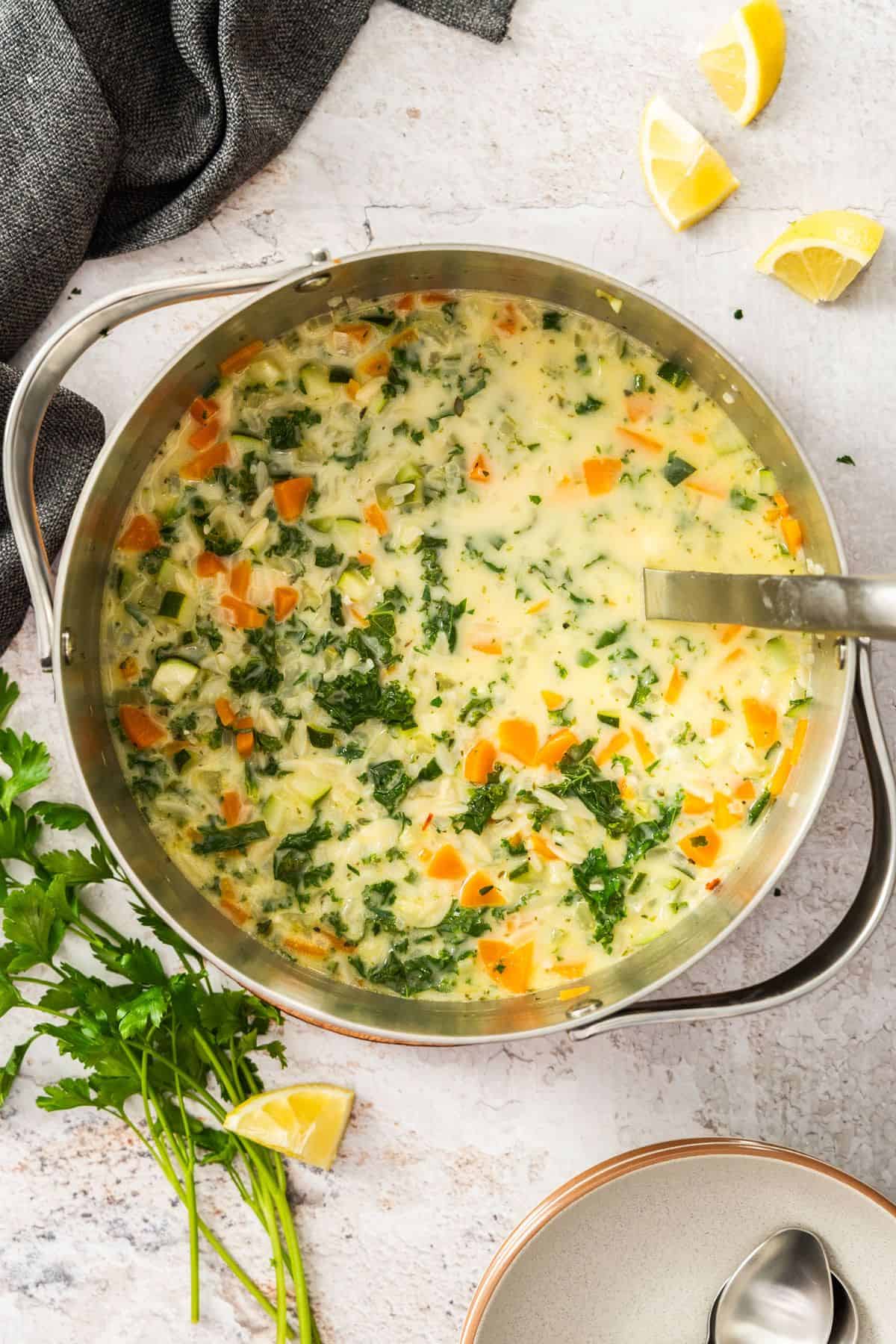 Large saucepan with Creamy Orzo Vegetable Soup, with a soup ladle resting in the pot.
