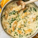 Large frying pan with Creamy Mustard and Spinach Chicken, with a wooden spoon resting in the pan.