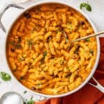 Large frying pan of Creamy Red Pepper Pasta, with a spoon resting in the pan.