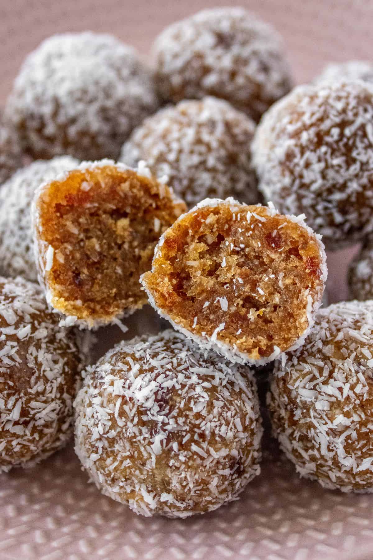 Plate of Peanut Butter Bliss Balls, with one cut in half to show the inside.