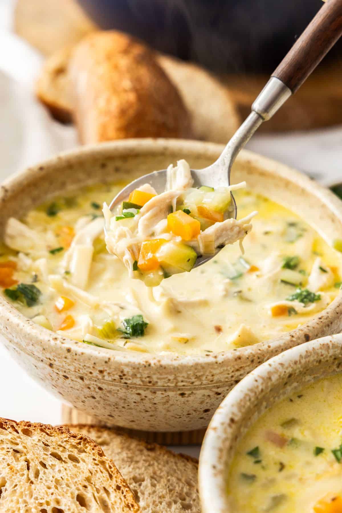 Bowl of Creamy Chicken Noodle Soup with a spoon lifting up some soup.