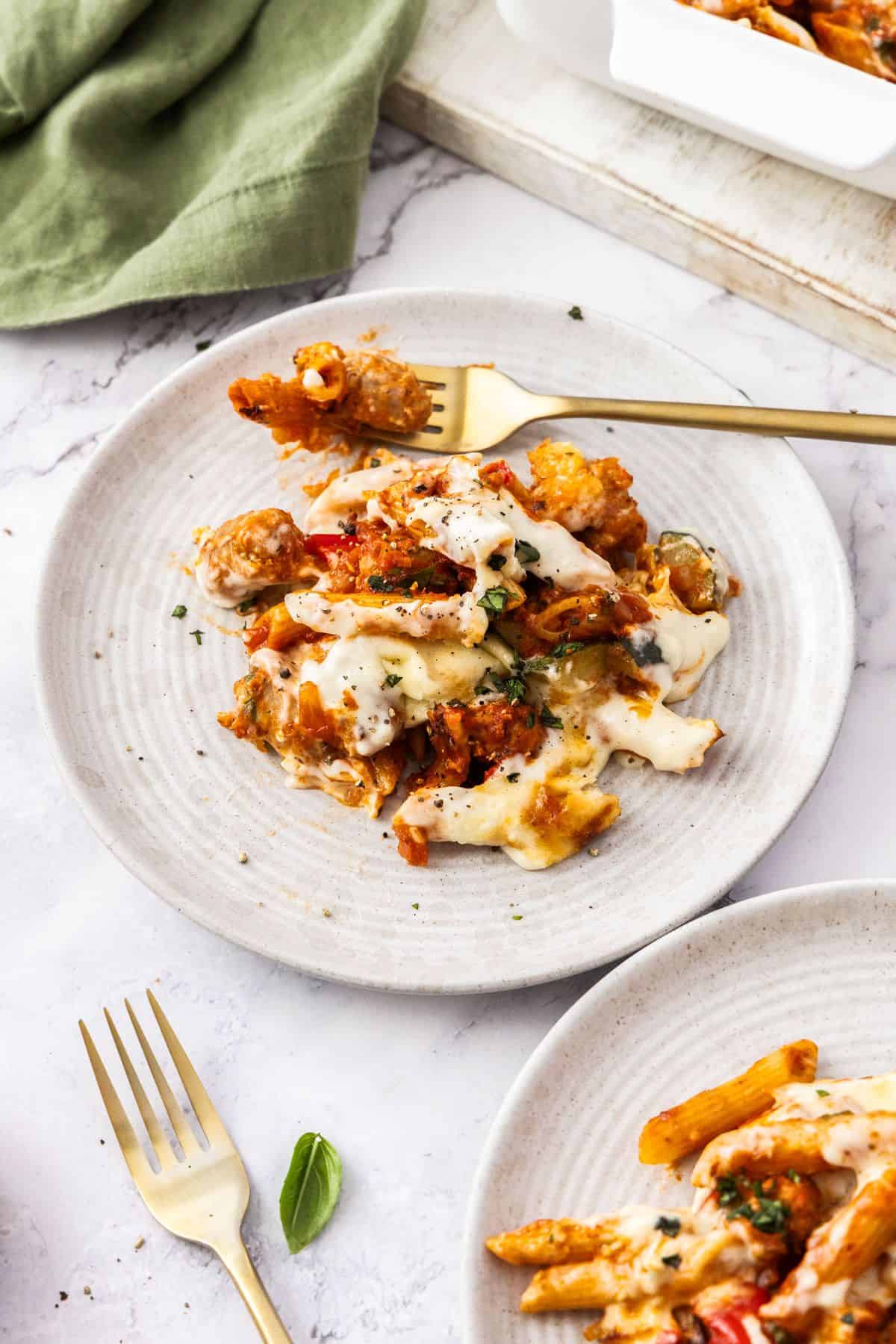 Serve of Mediterranean Sausage Pasta Bake on a round white plate, with a fork on the edge.