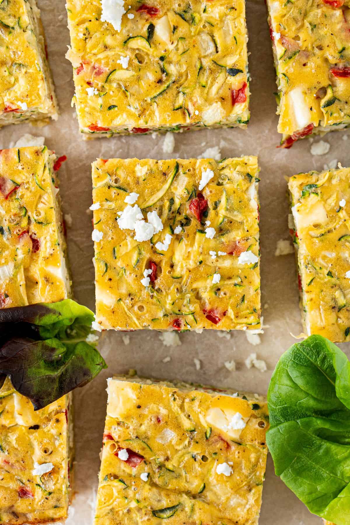 Zucchini Slice cut into squares, with some feta crumbled over the top and a couple of lettuce leaves.
