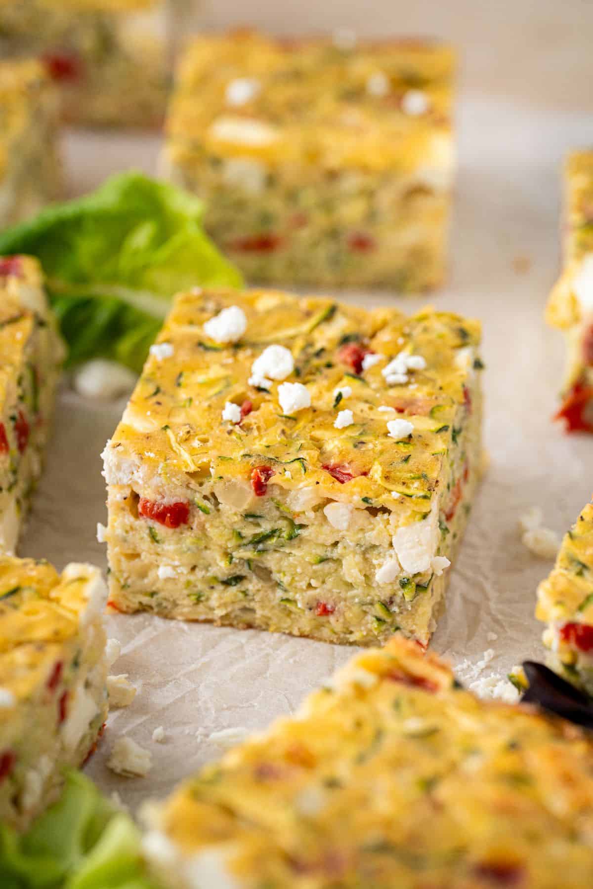 Zucchini Slice cut into squares, with some feta crumbled over the top and a couple of lettuce leaves.