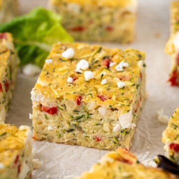 Zucchini Slice cut into squares, with some feta crumbled over the top and a couple of lettuce leaves.