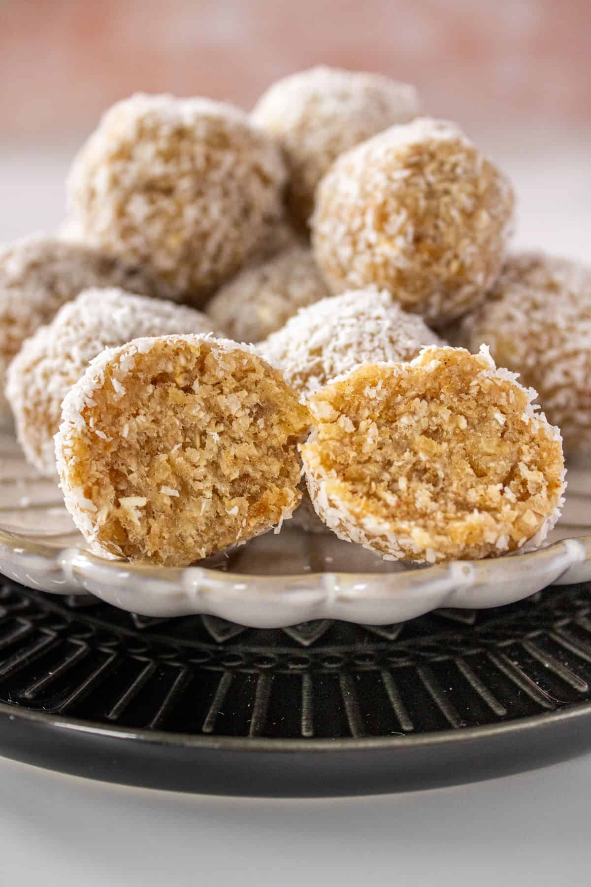 Two plates, one black and one white, with a pile of Pear Bliss Balls on top, one cut in half to show the inside.