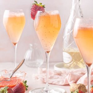 Three champagne glasses containing Strawberry Prosecco, one garnished with a strawberry.