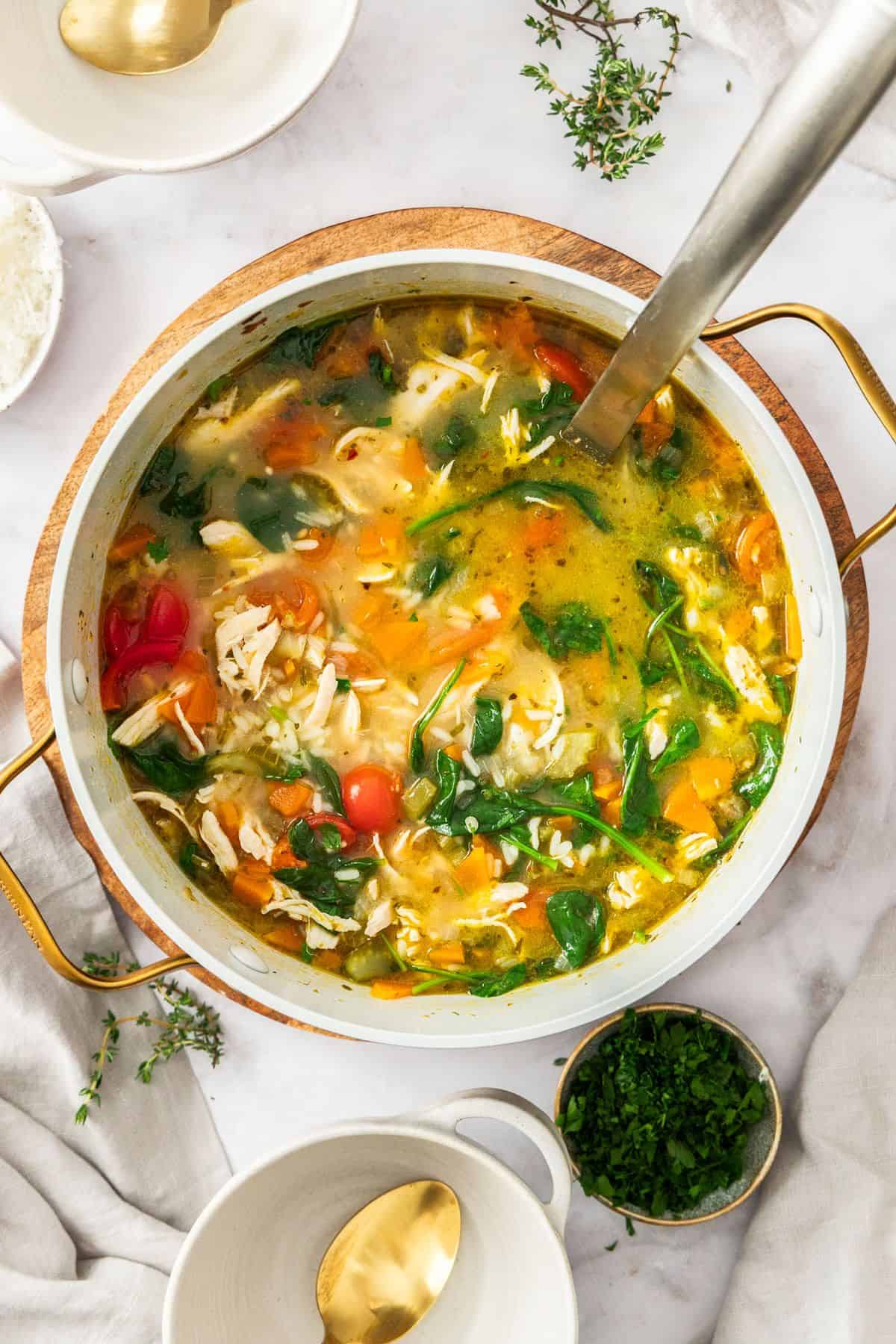Large saucepan of Mediterranean Chicken and Rice Soup, with a ladle resting in the pot.