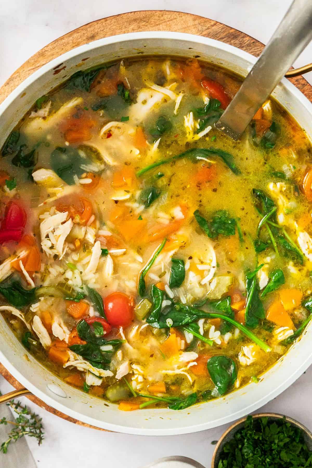 Large saucepan of Mediterranean Chicken and Rice Soup, with a ladle resting in the pot.
