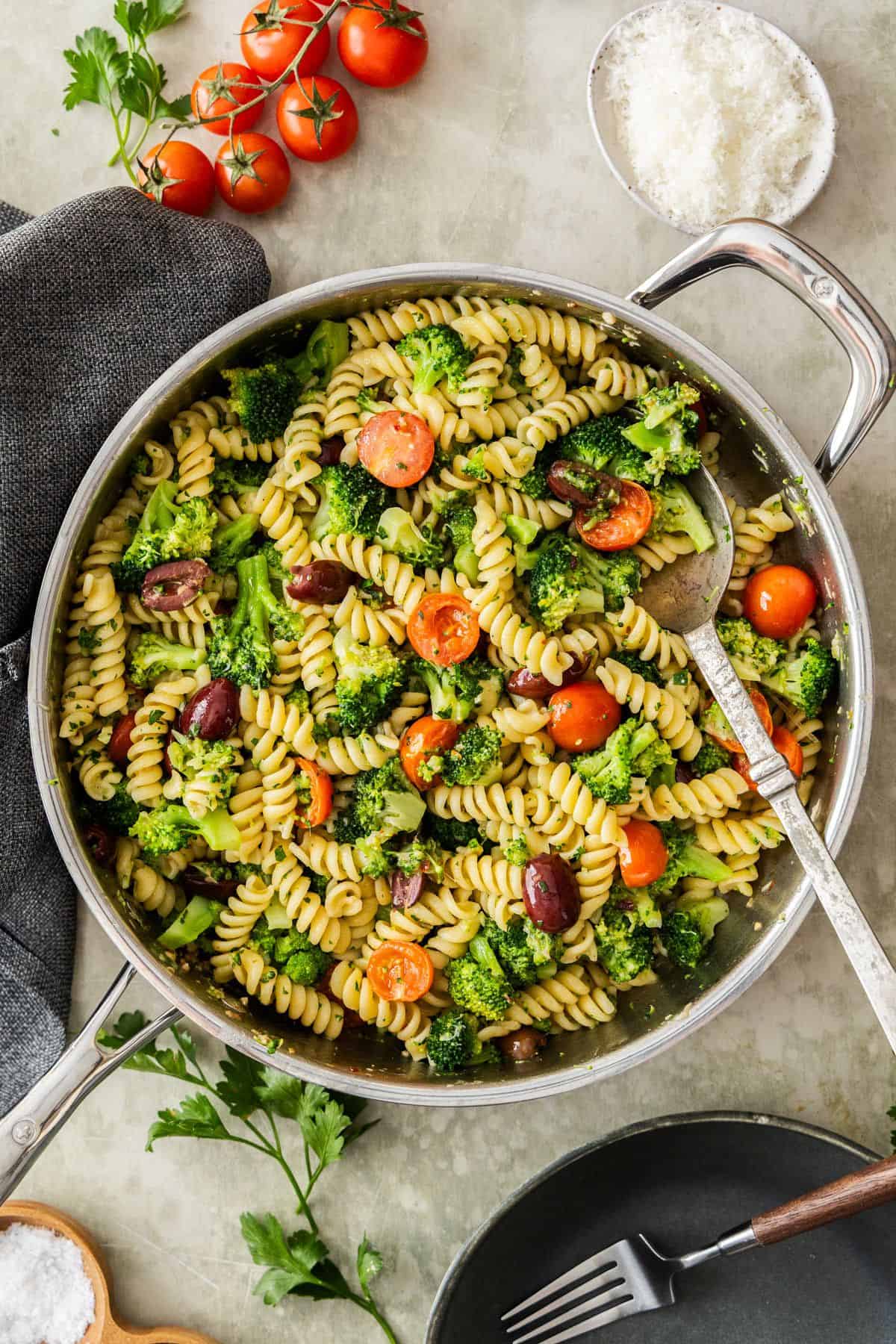 Large frying pan of Broccoli and Tomato Pasta with a spoon resting in the pan.