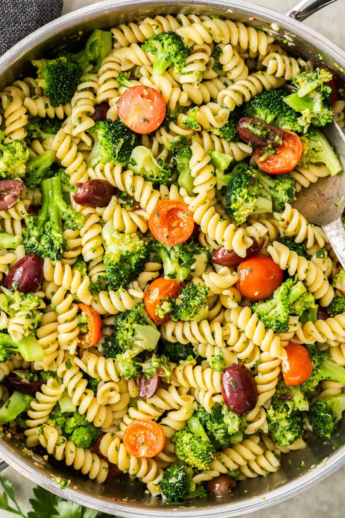 Large frying pan of Broccoli and Tomato Pasta with a spoon resting in the pan.